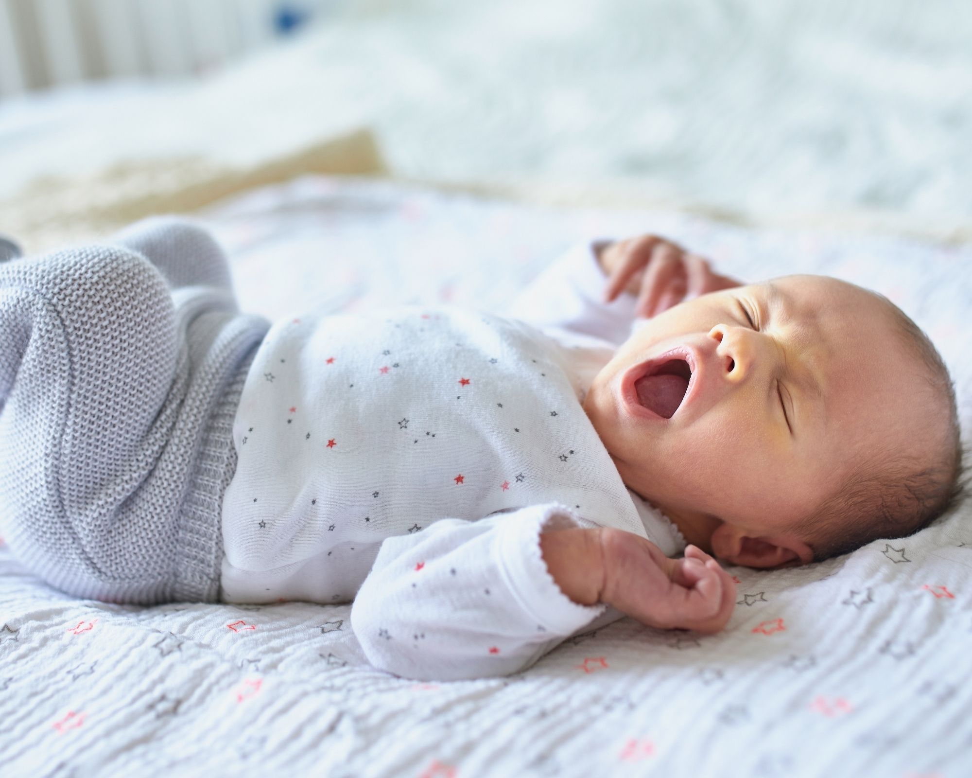 Baby liegt auf dem Rücken und gähnt