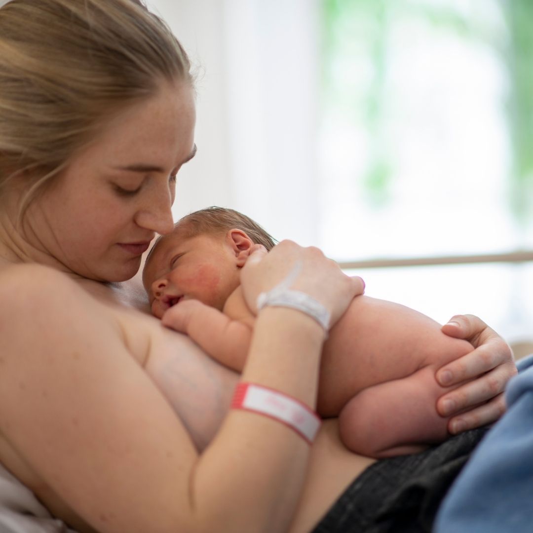 Bonding - eine Mutter hat ihr Neugeborenes auf sich liegen