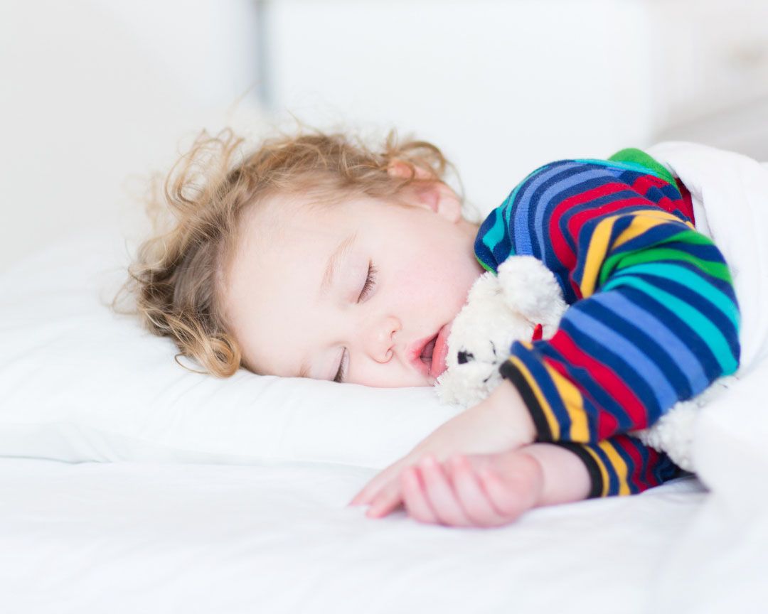 Kleinkind schläft und kuschelt dabei ein Kuscheltier